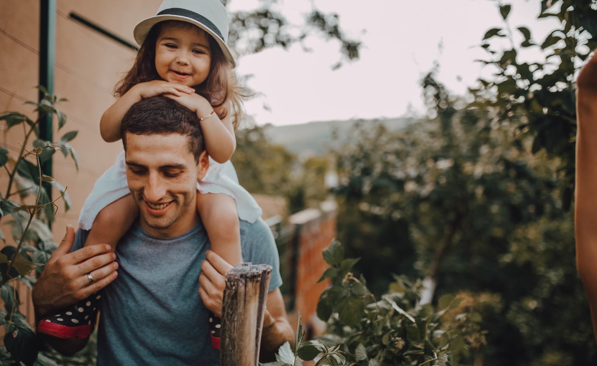 Mann mit Kind auf den Schultern im Garten