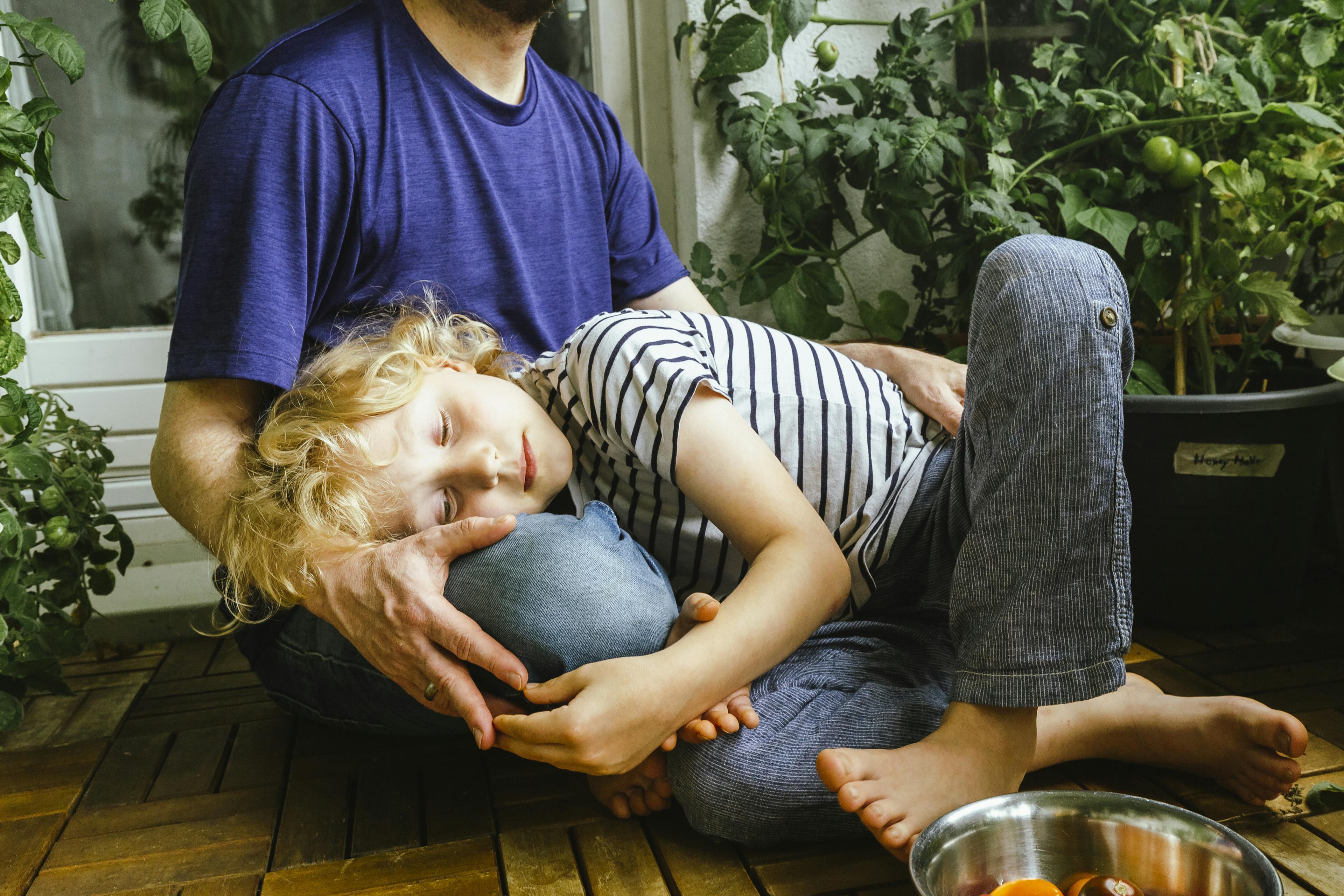 Ein Kind liegt auf dem Schoß eines Erwachsenen im Schneidersitz.